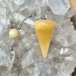 Orangencalcit Pendel – Ihr Werkzeug für spirituelle Klarheit und Harmonie Größe: Orangencalcit Pendel: ca. 3,4 cm lang, etwa 1,8 cm dick Orangencalcit Kugel: ca. 8 mm groß Kette: ca. 18 cm lang Beschreibung: Entdecken Sie die faszinierende Welt der Esoterik mit unserem Orangencalcit Pendel. Dieses wunderschöne Pendel, gefertigt aus echtem Orangencalcit, besticht durch seine natürliche Schönheit und die sorgfältige Verarbeitung. Der Orangencalcit, bekannt für seine leuchtende orange Farbe und seine energetischen Eigenschaften, wurde in eine elegante Pendelform geschliffen, die an einer nickelfreien, silberfarbenen Kette befestigt ist. Diese Kette, mit einer Länge von etwa 18 cm, ermöglicht eine leichte und angenehme Handhabung. Am oberen Ende der Kette befindet sich eine praktische Haltekugel, ebenfalls aus Orangencalcit, die einen sicheren und bequemen Griff bietet. Das Orangencalcit Pendel ist nicht nur ein ästhetisches Schmuckstück, sondern auch ein kraftvolles Werkzeug für spirituelle Praktiken. Seit über 4000 Jahren wird das Pendeln als Methode zur Weissagung, als Ratgeber und zur Entscheidungsfindung genutzt. Ob Sie nach Antworten auf wichtige Lebensfragen suchen oder Ihre spirituelle Praxis vertiefen möchten, dieses Pendel bietet Ihnen eine Verbindung zur energetischen Kraft des Orangencalcits. Symbolik: Der Orangencalcit ist in der Esoterik für seine fördernde Wirkung auf Lebensfreude und Optimismus bekannt. Er wird oft verwendet, um Blockaden zu lösen, Kreativität zu fördern und eine positive Lebenseinstellung zu unterstützen. In Kombination mit dem Pendel kann der Orangencalcit helfen, klare und intuitive Antworten zu finden, indem er den Energiefluss harmonisiert und die Verbindung zu den eigenen inneren Weisheiten stärkt. Das Pendel dient als eine Brücke zwischen dem bewussten Verstand und dem Unterbewusstsein und kann Ihnen helfen, Klarheit und Harmonie in Ihrem Leben zu schaffen. Foto und Lieferumfang: Orangencalcit Pendel
