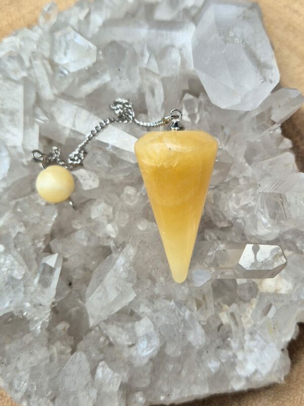 Orangencalcit Pendel – Ihr Werkzeug für spirituelle Klarheit und Harmonie Größe: Orangencalcit Pendel: ca. 3,4 cm lang, etwa 1,8 cm dick Orangencalcit Kugel: ca. 8 mm groß Kette: ca. 18 cm lang Beschreibung: Entdecken Sie die faszinierende Welt der Esoterik mit unserem Orangencalcit Pendel. Dieses wunderschöne Pendel, gefertigt aus echtem Orangencalcit, besticht durch seine natürliche Schönheit und die sorgfältige Verarbeitung. Der Orangencalcit, bekannt für seine leuchtende orange Farbe und seine energetischen Eigenschaften, wurde in eine elegante Pendelform geschliffen, die an einer nickelfreien, silberfarbenen Kette befestigt ist. Diese Kette, mit einer Länge von etwa 18 cm, ermöglicht eine leichte und angenehme Handhabung. Am oberen Ende der Kette befindet sich eine praktische Haltekugel, ebenfalls aus Orangencalcit, die einen sicheren und bequemen Griff bietet. Das Orangencalcit Pendel ist nicht nur ein ästhetisches Schmuckstück, sondern auch ein kraftvolles Werkzeug für spirituelle Praktiken. Seit über 4000 Jahren wird das Pendeln als Methode zur Weissagung, als Ratgeber und zur Entscheidungsfindung genutzt. Ob Sie nach Antworten auf wichtige Lebensfragen suchen oder Ihre spirituelle Praxis vertiefen möchten, dieses Pendel bietet Ihnen eine Verbindung zur energetischen Kraft des Orangencalcits. Symbolik: Der Orangencalcit ist in der Esoterik für seine fördernde Wirkung auf Lebensfreude und Optimismus bekannt. Er wird oft verwendet, um Blockaden zu lösen, Kreativität zu fördern und eine positive Lebenseinstellung zu unterstützen. In Kombination mit dem Pendel kann der Orangencalcit helfen, klare und intuitive Antworten zu finden, indem er den Energiefluss harmonisiert und die Verbindung zu den eigenen inneren Weisheiten stärkt. Das Pendel dient als eine Brücke zwischen dem bewussten Verstand und dem Unterbewusstsein und kann Ihnen helfen, Klarheit und Harmonie in Ihrem Leben zu schaffen. Foto und Lieferumfang: Orangencalcit Pendel